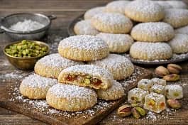 طريقة-عمل-كحك العيد المحشو بالملبن والفستق، مع سكر بودرة وقطع ملبن شفافة على الجانب