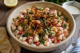 طريقة-عمل-سلطة حمص لبنانية مع الطحينة الكريمية والبصل المحمر الذهبي، تقدم في طبق فخاري مع خبز عربي ورمان