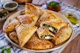طريقة-عمل-معجنات فلسطينية بالزعتر الأخضر والجبنة البيضاء الذائبة، ذهبية اللون ومخبوزة على صينية مع كوب شاي نعناع