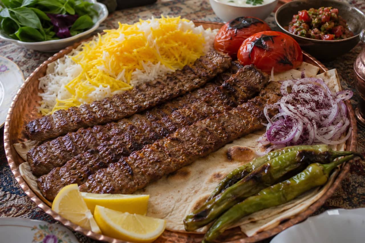 طبق نحاسي إيراني يحمل أسياخ كباب كوبيده الطويلة والعريضة المشوية على الفحم، لونها بني ذهبي تظهر عليها بقع سوداء من الجمر، تقدم فوق خبز التافتون أو اللافاش مع أرز زعفراني مفلفل، مزينة بشرائح الطماطم المشوية والفلفل الأخضر الحار وشرائح البصل السماقي والليمون، على مائدة فارسية تقليدية
