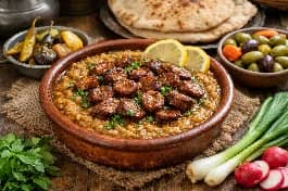 طريقة-عمل-طبق فول مدمس بالسجق الشرقي المحمر، مع حلقات السجق البنية فوق الفول المهروس ومزين بزيت الزيتون والبقدونس