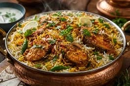 طبق برياني سمك باكستاني فاخر، أرز بسمتي ذهبي طويل الحبة مفلفل مع قطع سمك متبلة ببهارات لاهور، مزين بالزعفران المنقوع، جوز الهند المحمص، أوراق الكزبرة والنعناع، والفلفل الأخضر الحار، في قدر نحاسي تقليدي