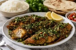 طبق سمك يمني مقلي عميقاً مع صلصة حارة بالكزبرة والثوم، قطع سمك ذهبية مقرمشة مغطاة بصلصة خضراء حارة، يقدم مع أرز بسمتي وخبز يمني وشرائح ليمون