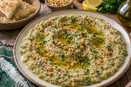 طبق متبل كوسا بالطحينة والثوم المدخن جزائري بقوام كريمي متماسك، مزين بزيت الزيتون والصنوبر المحمص والبقدونس الطازج