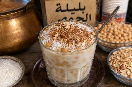 طريقة-عمل-طبق بليلة الحمص الحب المصرية ساخنة في كأس زجاجي مزينة بجوز الهند والقرفة والمكسرات