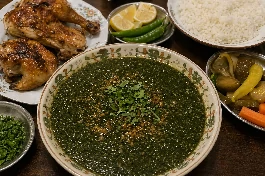 طريقة-عمل-طبق ملوخية خضراء مخملية القوام تعلوها زفرة الثوم والكزبرة الذهبية، بجانب أرز أبيض مفلفل وقطع دجاج بلدي مشوي، في مشهد يعكس أصالة السفرة المصرية