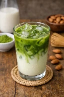 طريقة-عمل-ماتشا لاتيه بارد بحليب اللوز يُقدَّم في كوب زجاجي مع مكعبات ثلج ولون أخضر زاهي