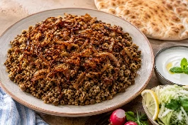 طبق مجدّرة خضراء لبنانية بالعدس والبصل المحمر، عدس بني متماسك مع برغل خشن مفلفل وبصل ذهبي مقرمش، يقدم مع لبن زبادي بارد وسلطة ملفوف