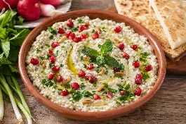 طريقة-عمل-طبق متبل لبناني في صحن فخاري مسطح، الباذنجان المدخن مهروس بقوام كريمي ناعم ممزوج بالطحينة واللبن، مزين بخطوط من زيت الزيتون البكر، حبات الرمان الحمراء، وأوراق النعناع الطازج، مع خبز عربي محمص على الجانب