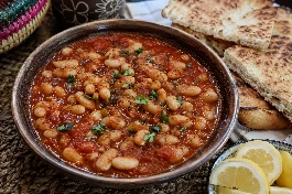 طبق فاصوليا بيضاء بالطماطم والثوم ليبي، بقوام كريمي كثيف في صلصة طماطم حمراء غنية مع زيت الزيتون البكر، يقدم مع خبز ليبي محمص وشرائح ليمون