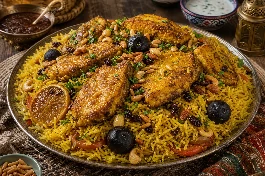 طبق مقلوبة سمك عماني ذهبي يظهر طبقات الأرز البسمتي المفلفل وقطع السمك المقلي المتماسك، مزين باللومي واللوز والصنوبر والبقدونس