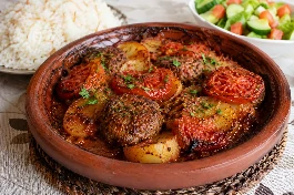 طريقة-عمل-طاجن كفتة عُماني بطبقات من أقراص الكفتة والبطاطس المحمرة والطماطم المكرملة، يقدم في طبق فخاري مع أرز أبيض وسلطة