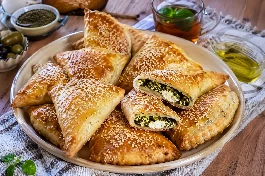 طريقة-عمل-معجنات فلسطينية بالزعتر الأخضر والجبنة البيضاء الذائبة، ذهبية اللون ومخبوزة على صينية مع كوب شاي نعناع