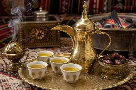 طريقة-عمل-دلة قهوة عربية سعودية ذهبية اللون مع فنجان قهوة أشقر وبخور وفنجان تمر في مجلس عربي