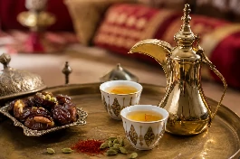 فنجان قهوة بيضاء سعودية بالزعفران والهيل بلون أشقر ذهبي، يقدم في دلة تقليدية مع فنجان فاخر وحبات هيل وورود، في مجلس عربي مزين