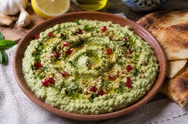 طريقة-عمل-متبل فول أخضر سوري كريمي بالثوم والليمون، مزين بزيت الزيتون والكمون وحب الرمان، يقدم في طبق فخاري مع خبز عربي محمص