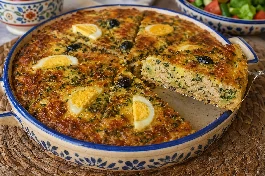 طاجين تونس بالدجاج والجبن والبقدونس ذهبي محمر ومتماسك مقطع مثلثات في طبق تقليدي