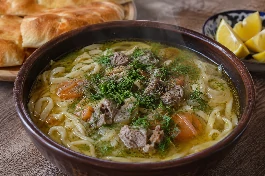 وعاء فخاري عميق من حساء الفوبو الأوزبكي الغني، تطفو فيه شعيرية يدوية سميكة وقطع لحم خروف مطهوة ببطء وشرائح جزر وبصل في مرق ذهبي معطر بالكمون، يزينه الشبت الطازج والفلفل الأسود