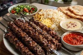 طريقة-عمل-أسياخ كباب لحم يمني غنية بالبهارات والصنوبر، مشوية على الفحم ومدخنة، مقدمة مع الأرز والسلطة وخبز التنور