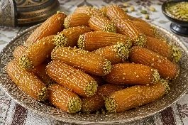 طريقة-عمل-قطع من صوابع زينب الذهبية المقلية في قطر كثيف مزينة بالفستق الحلبي الأخضر وتقدم في طبق تراثي